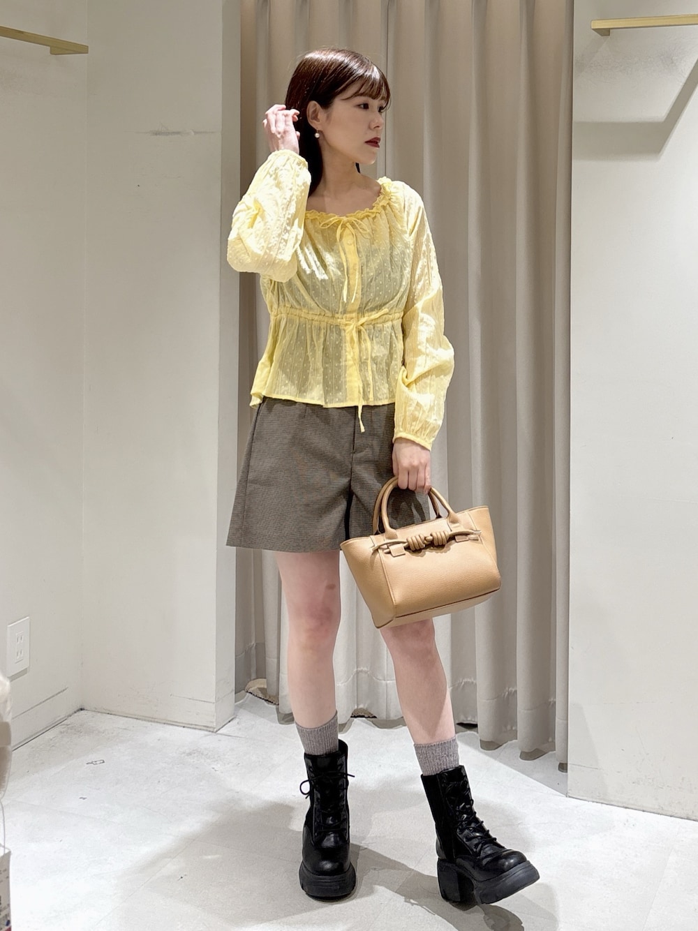 イエロー系のシャツ/ブラウス、ブラック系のブーツ、ベージュ系のハンドバッグを着用したレディースの冬コーディネートの1枚目の写真