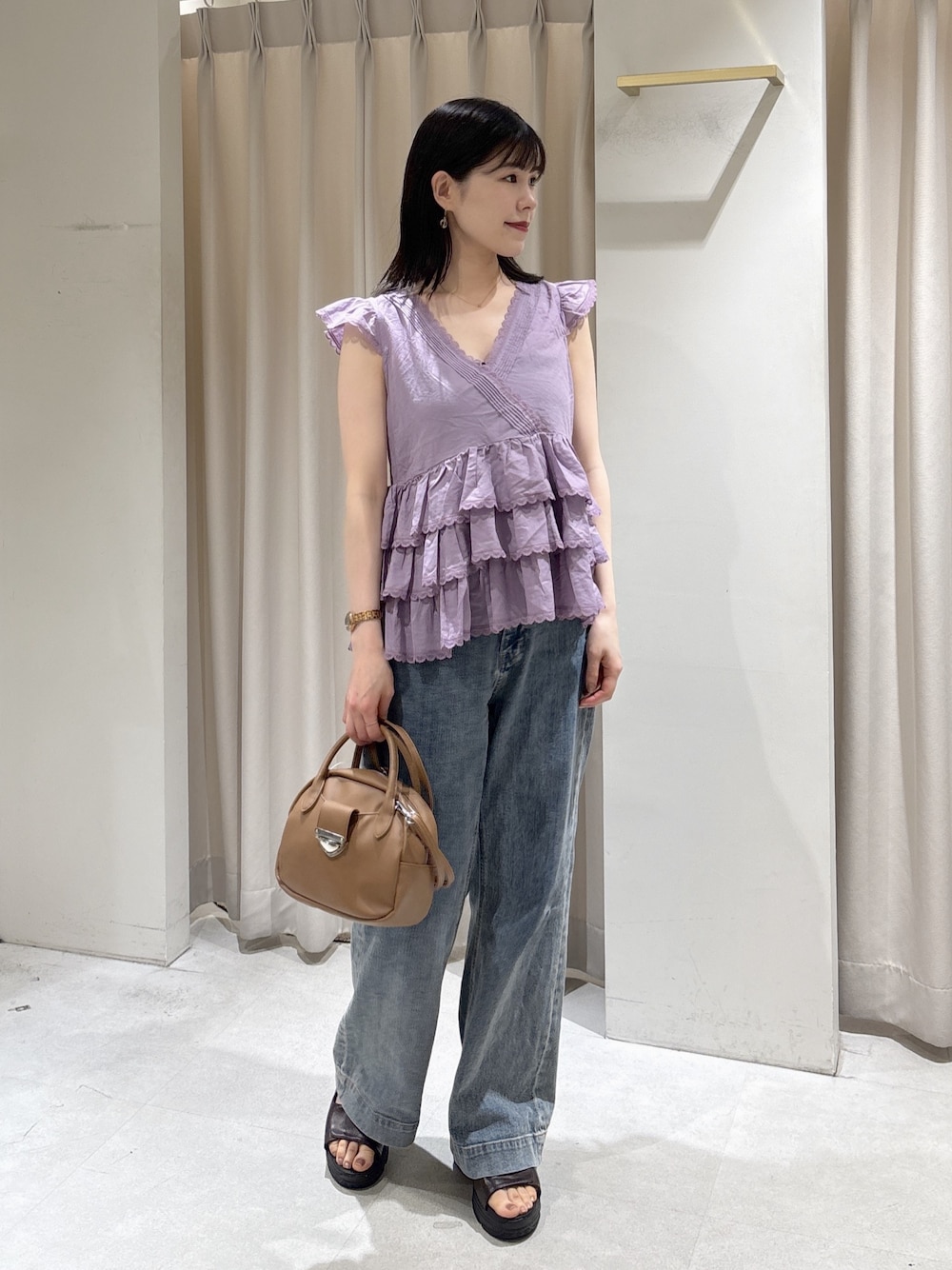 パープル系のシャツ/ブラウス、ブラウン系のハンドバッグ、ブルー系のデニムパンツを着用したレディースの夏コーディネートの1枚目の写真