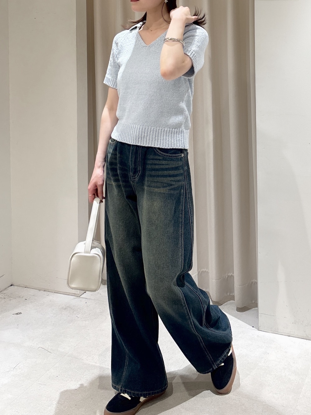 ブルー系のニット/セーター、ブルー系のデニムパンツ、ホワイト系のハンドバッグを着用したレディースの春コーディネートの1枚目の写真