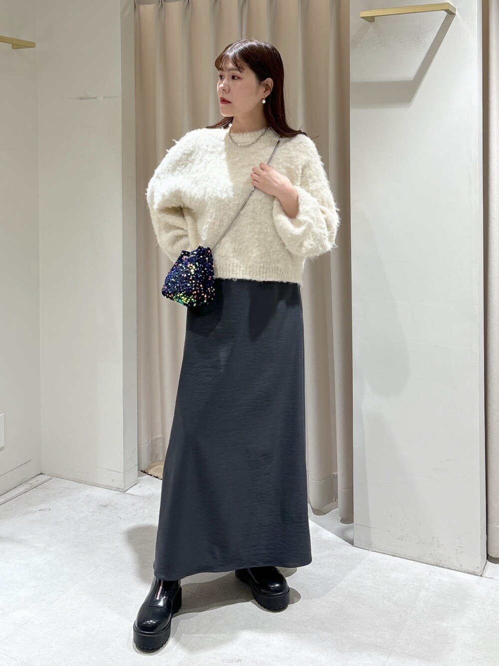 ブラック系のショルダーバッグ、グレー系のスカート、ブラック系のブーツを着用したレディースの冬コーディネートの1枚目の写真