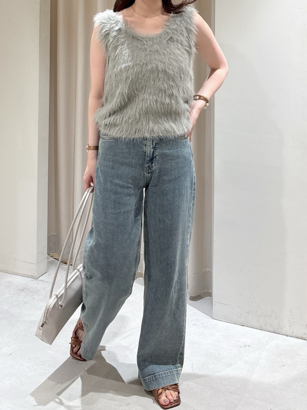 ベージュ系のニット/セーター、ブルー系のデニムパンツ、ブラウン系のサンダルを着用したレディースの夏コーディネートの1枚目の写真