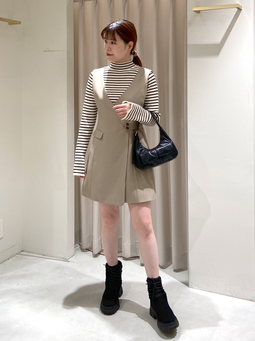 ベージュ系のワンピース、ホワイト系のニット/セーター、ブラック系のショルダーバッグを着用したレディースの冬コーディネートの1枚目の写真