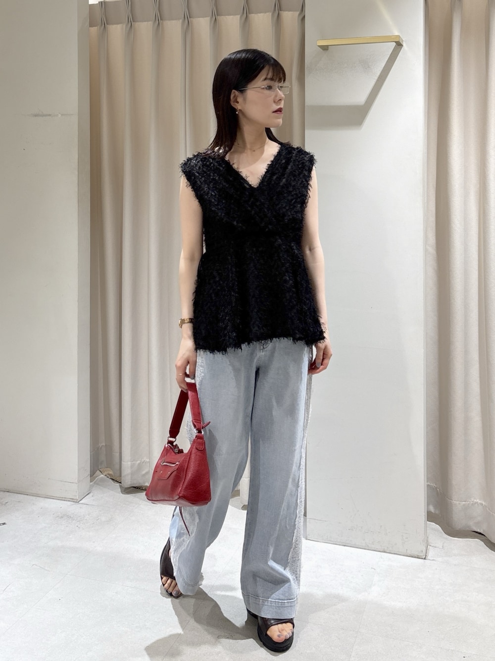 レッド系のショルダーバッグ、ブルー系のデニムパンツ、ブラウン系のサンダルを着用したレディースの夏コーディネートの1枚目の写真