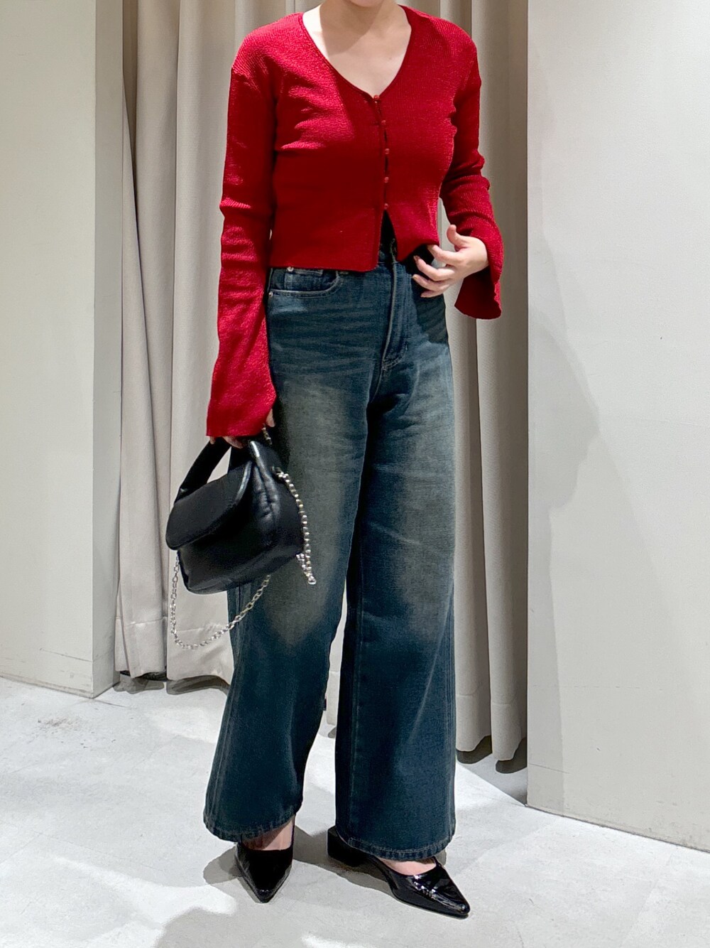 レッド系のニット/セーター、ブルー系のデニムパンツ、ブラック系のショルダーバッグを着用したレディースの秋コーディネートの1枚目の写真