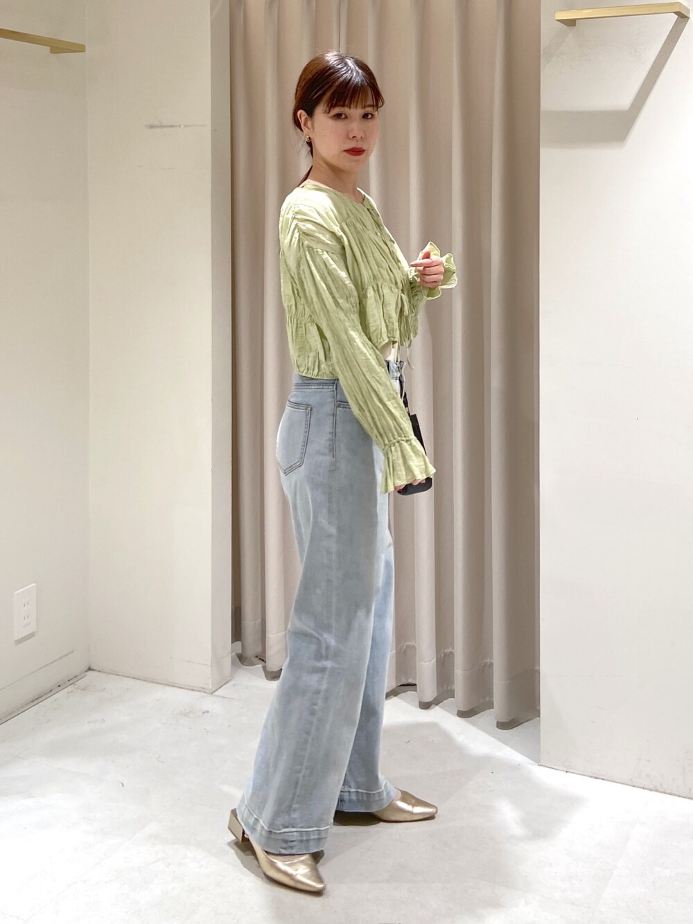 グリーン系のカーディガン/ボレロ、ブルー系のデニムパンツ、ホワイト系のタンクトップを着用したレディースの春コーディネートの1枚目の写真