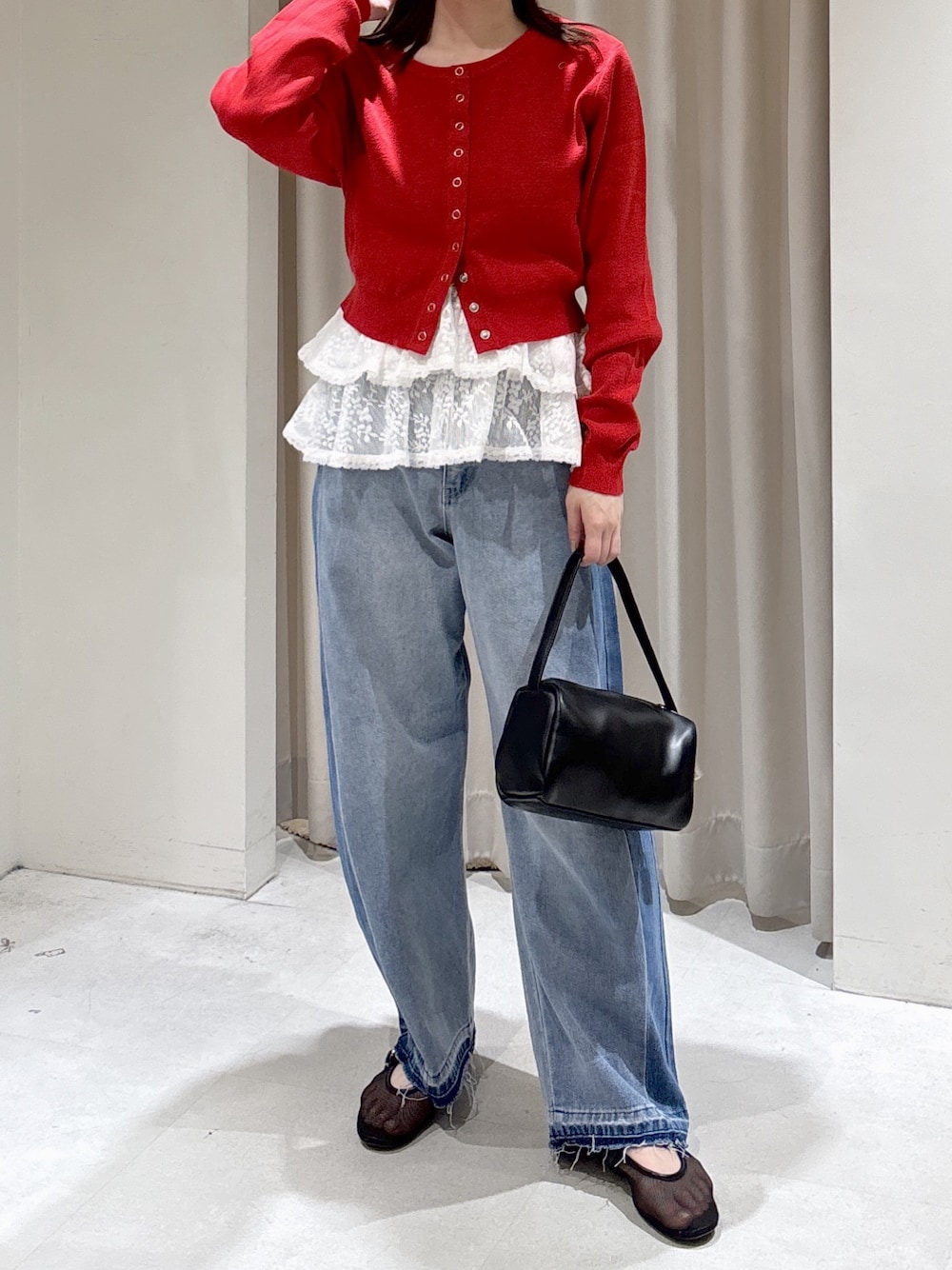 レッド系のニット/セーター、ホワイト系のシャツ/ブラウス、ブラック系のハンドバッグを着用したレディースの冬コーディネートの1枚目の写真