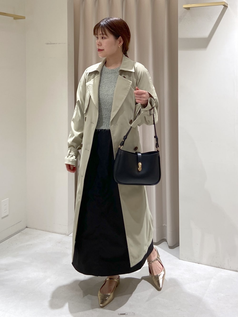 グリーン系のトレンチコート、ブラック系のショルダーバッグ、グリーン系のニット/セーターを着用したレディースの春コーディネートの1枚目の写真
