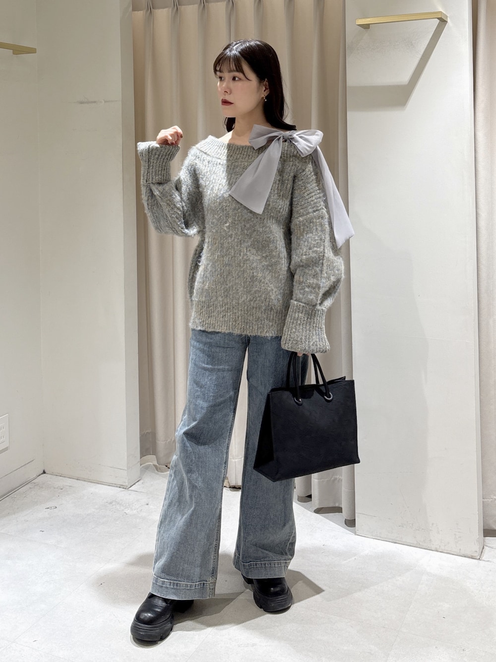 グレー系のニット/セーター、ブラック系のトートバッグ、ブルー系のデニムパンツを着用したレディースの冬コーディネートの1枚目の写真