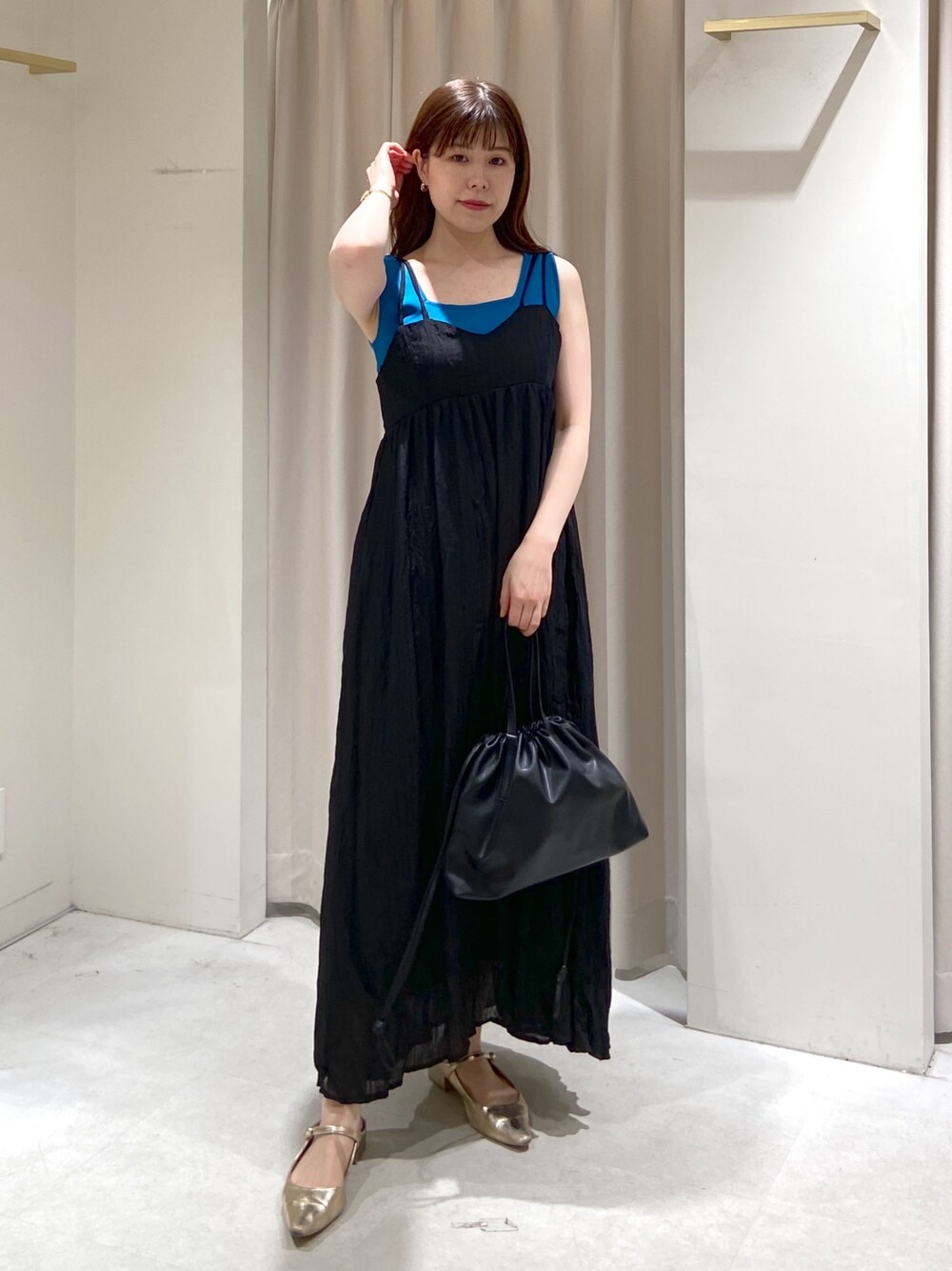 ブルー系のタンクトップ、ブラック系のハンドバッグ、ゴールド系のパンプスを着用したレディースの春コーディネートの1枚目の写真