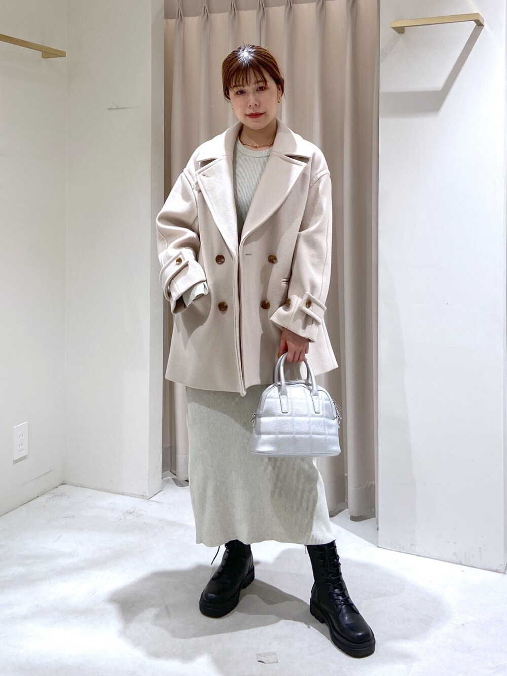 ベージュ系のピーコート、ブラック系のブーツ、シルバー系のショルダーバッグを着用したレディースの秋コーディネートの1枚目の写真