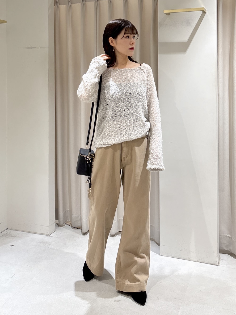 グレー系のニット/セーター、ブラック系のショルダーバッグ、ベージュ系のデニムパンツを着用したレディースの秋コーディネートの1枚目の写真