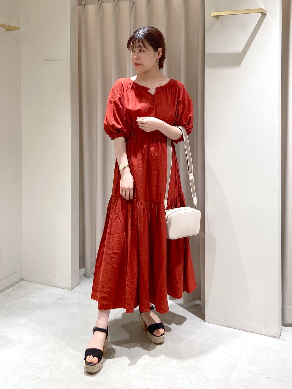 レッド系のワンピース、ホワイト系のボディバッグ/ウエストポーチ、ブラック系のサンダルを着用したレディースの春コーディネートの1枚目の写真