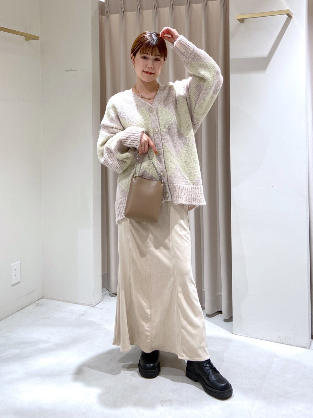 ベージュ系のショルダーバッグ、ブラック系のブーツ、ホワイト系のスカートを着用したレディースの秋コーディネートの1枚目の写真