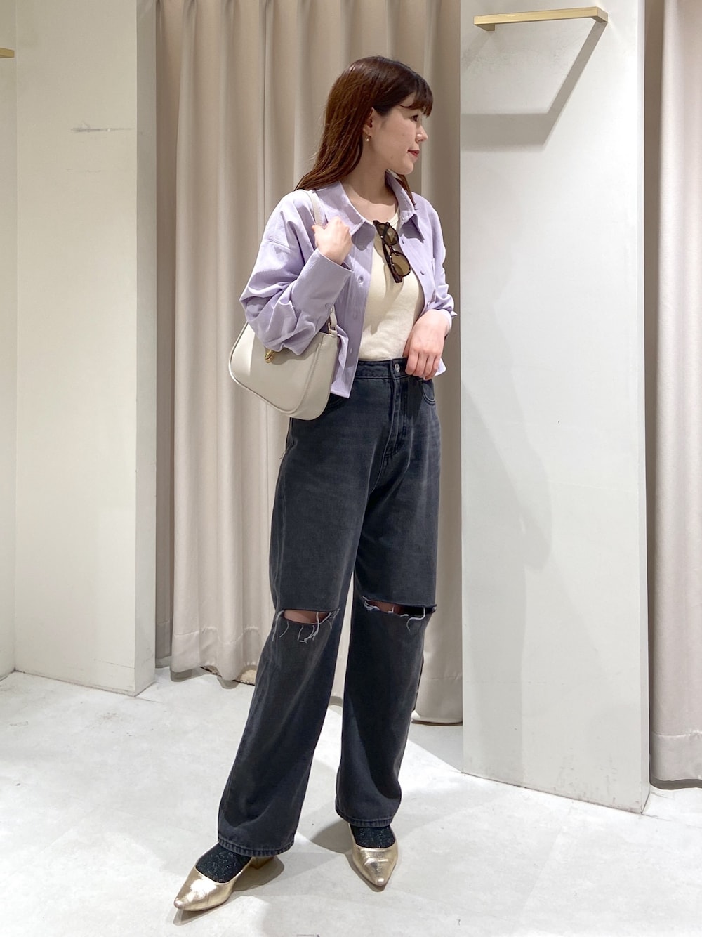 ブラック系のデニムパンツ、ゴールド系のパンプス、グレー系のショルダーバッグを着用したレディースの春コーディネートの1枚目の写真