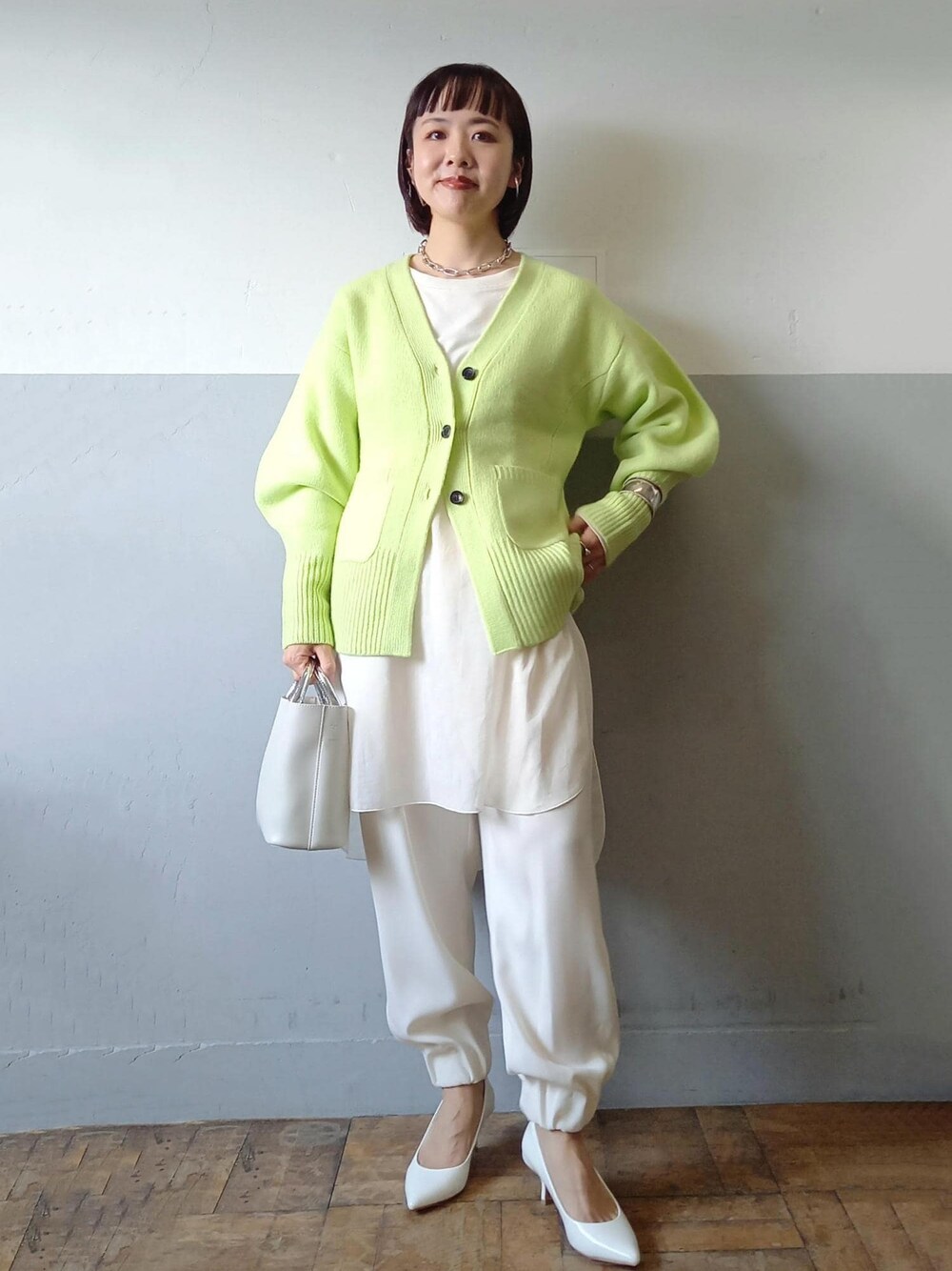ホワイト系のショルダーバッグ、グリーン系のカーディガン/ボレロ、ホワイト系のパンプスを着用したレディースの秋コーディネートの1枚目の写真