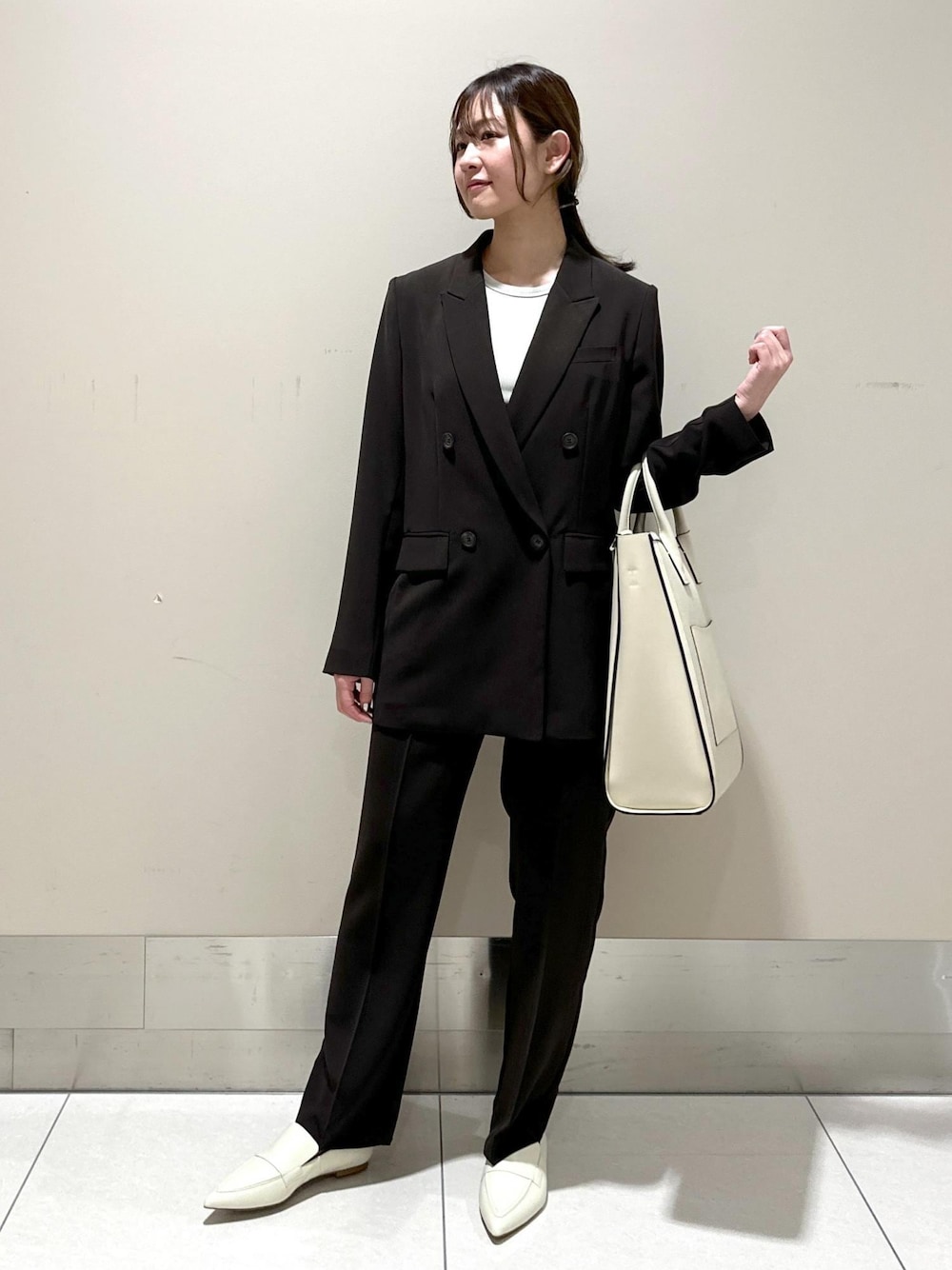 ベージュ系のトートバッグ、ホワイト系のパンプス、ブラウン系のその他パンツを着用したレディースの春コーディネートの1枚目の写真