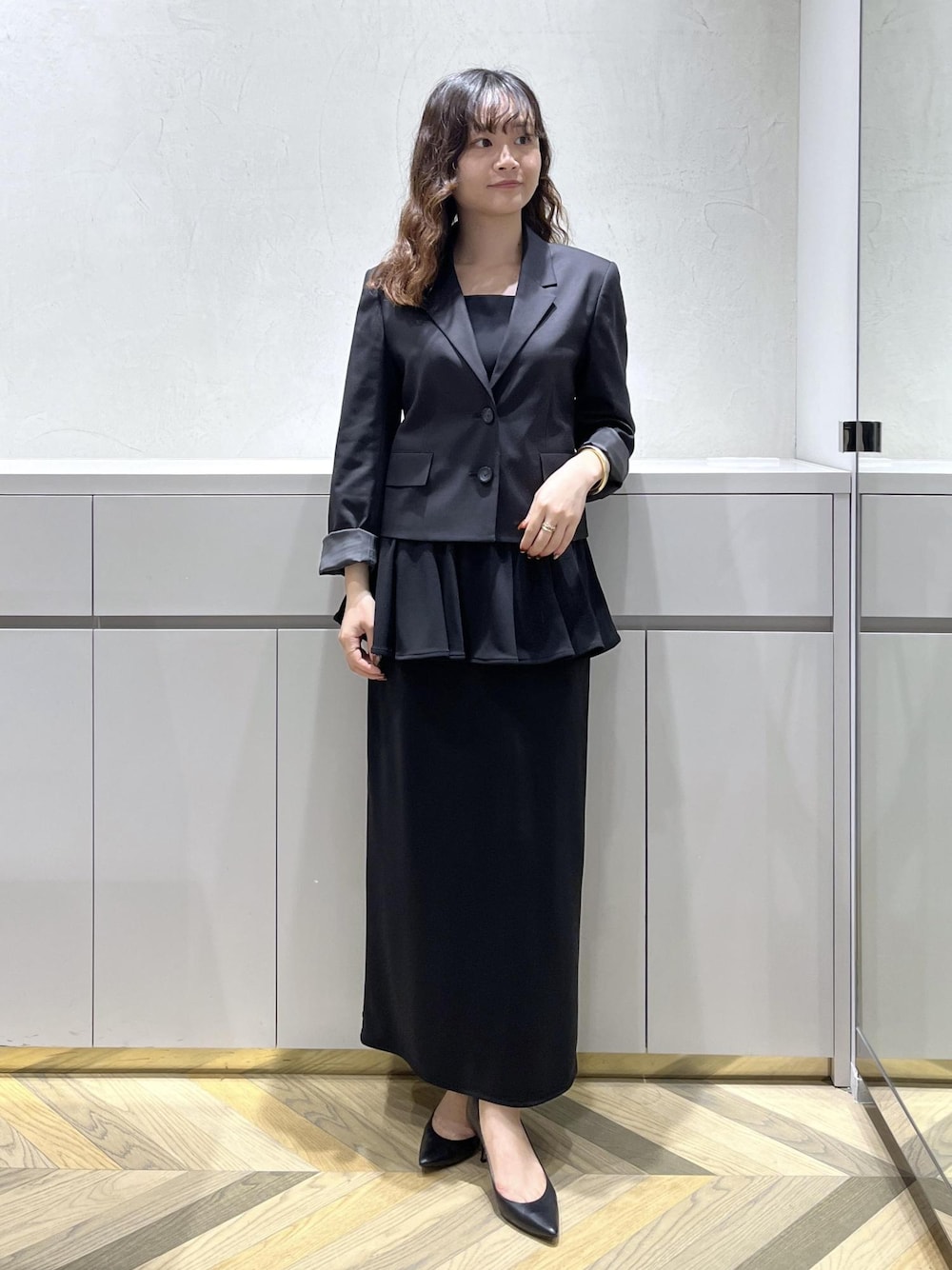 ブラック系のキャミソール、ブラック系のテーラードジャケット、ブラック系のスカートを着用したレディースの秋コーディネートの1枚目の写真