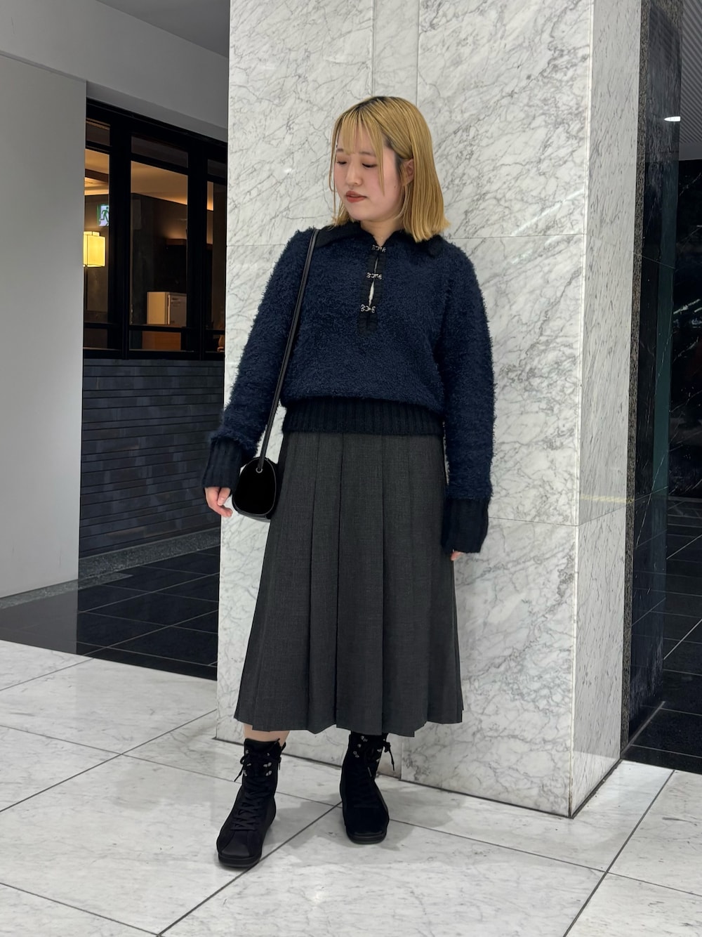 グレー系のスカート、ブルー系のニット/セーター、ブラック系のショルダーバッグを着用したレディースの秋コーディネートの1枚目の写真