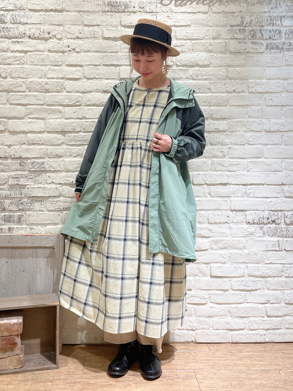 イエロー系のワンピース、グリーン系のマウンテンパーカー、ベージュ系のデニムパンツを着用したレディースの春コーディネートの1枚目の写真