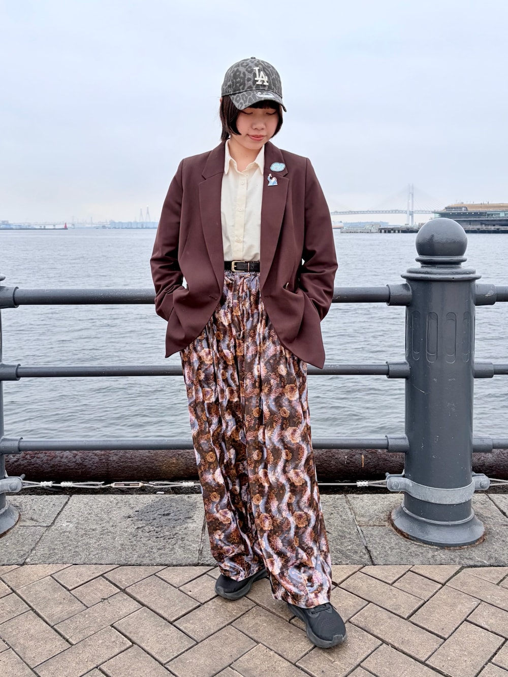 ブラウン系のテーラードジャケット、パープル系のパンツ、ブラック系のスニーカーを着用したレディースの春コーディネートの1枚目の写真