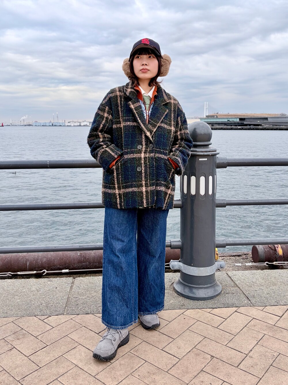 グリーン系のジャケット/アウター、オレンジ系のカーディガン/ボレロ、ブルー系のデニムパンツを着用したレディースの冬コーディネートの1枚目の写真