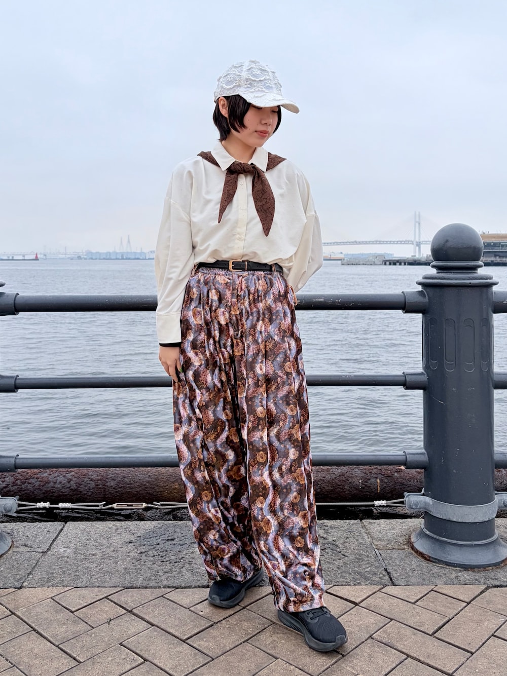 パープル系のパンツ、ブラック系のスニーカー、ホワイト系のキャップを着用したレディースの春コーディネートの1枚目の写真