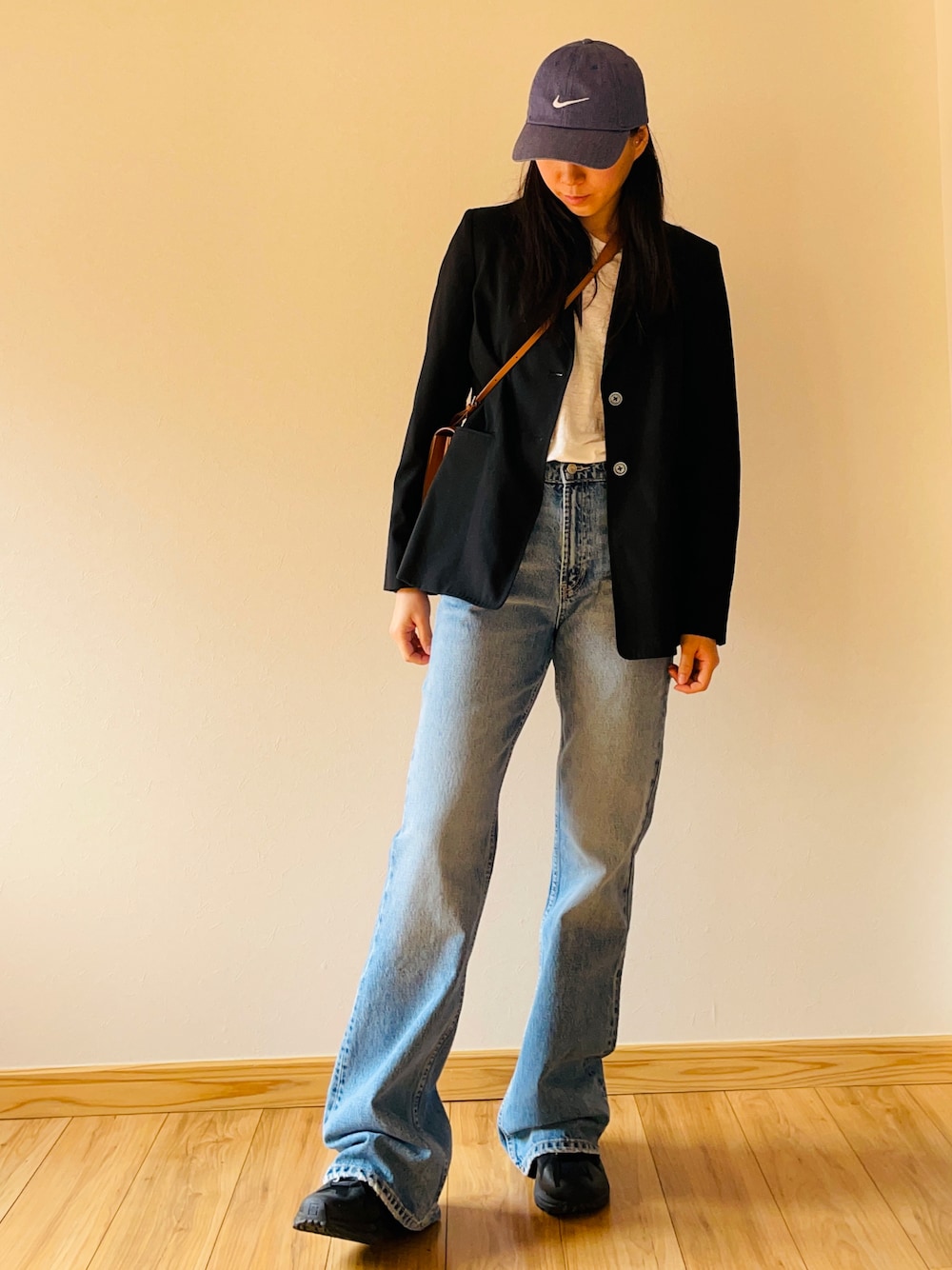 ブラック系のテーラードジャケット、ホワイト系のTシャツ/カットソー、ブラウン系のショルダーバッグを着用したレディースの春コーディネートの1枚目の写真