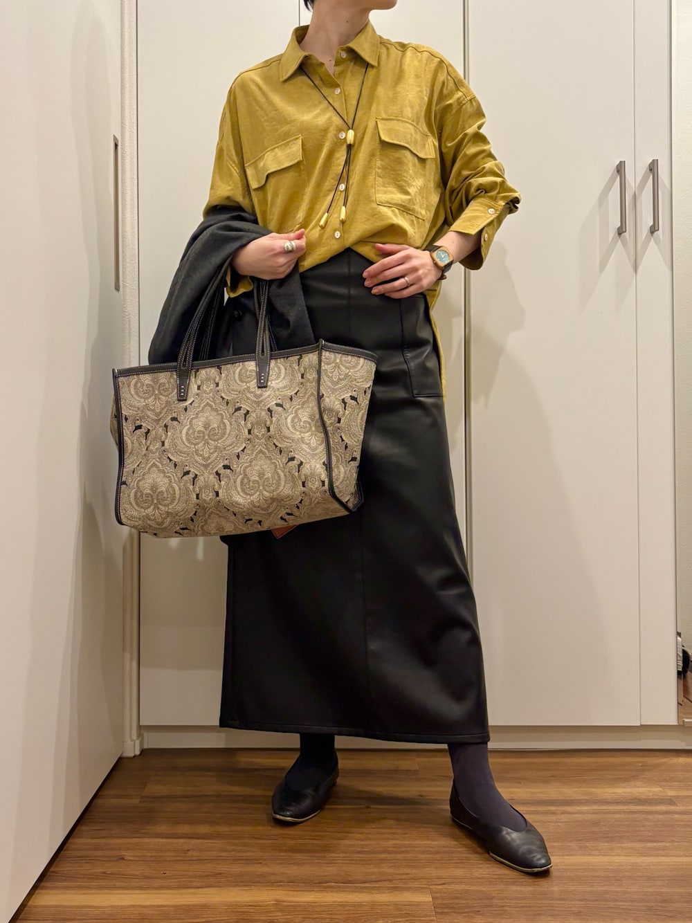 ブラック系のトートバッグ、イエロー系のシャツ/ブラウス、ブラック系のスカートを着用したレディースの秋コーディネートの1枚目の写真