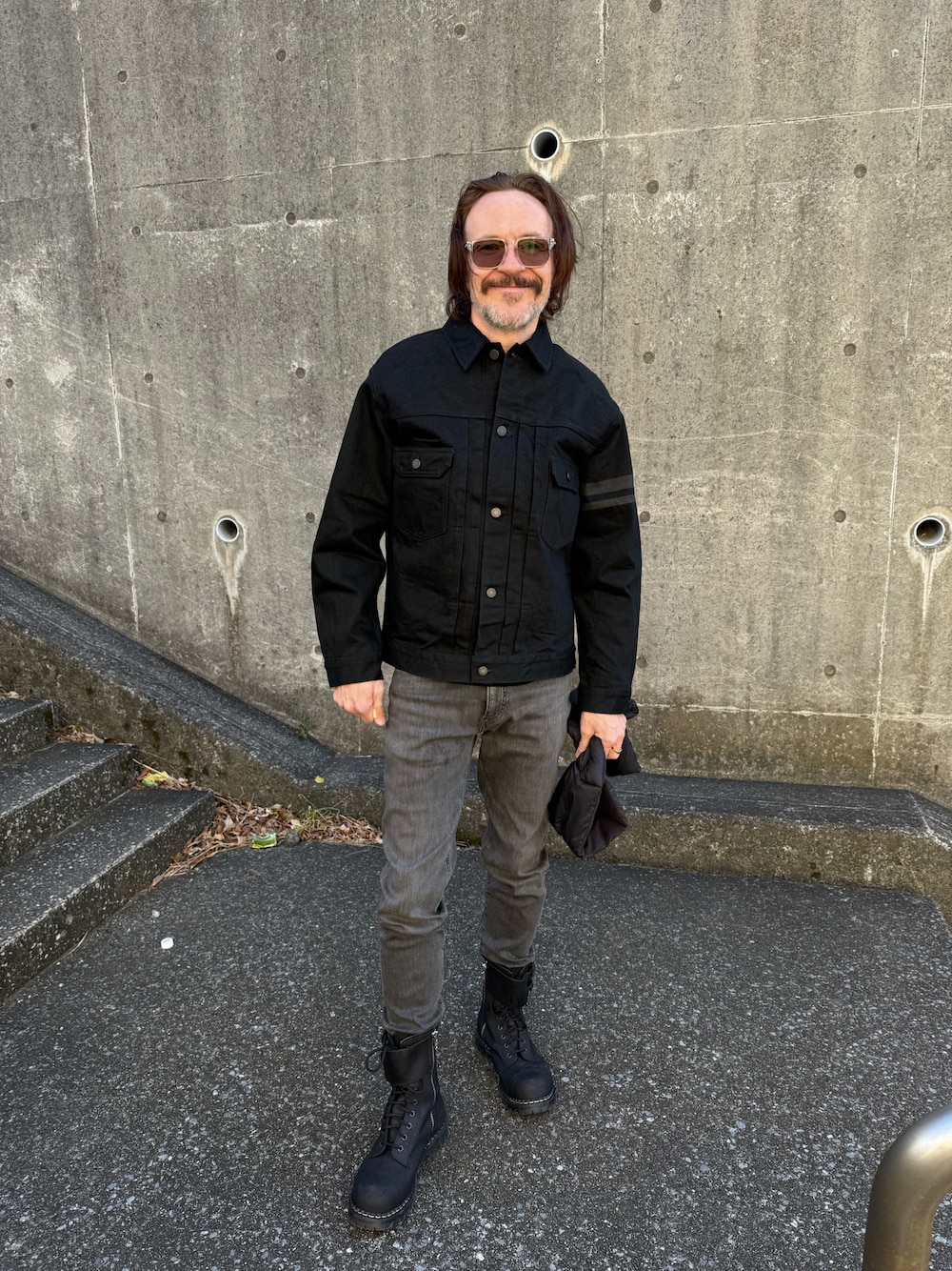 ブラック系のデニムジャケット、ブラック系のブーツ、グレー系のデニムパンツを着用したメンズの冬コーディネートの1枚目の写真