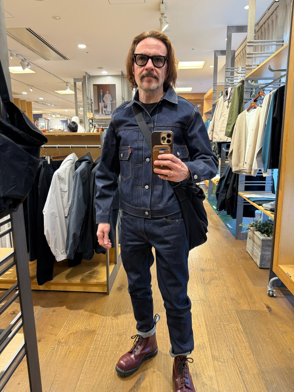 ブルー系のデニムパンツ、ブルー系のデニムジャケット、レッド系のブーツを着用したメンズの冬コーディネートの1枚目の写真