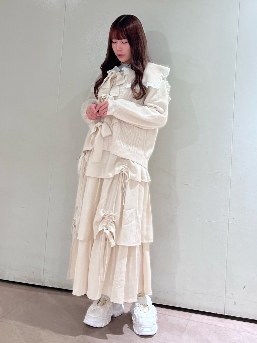 ホワイト系のカーディガン/ボレロ、グレー系のニット/セーター、ホワイト系のスカートを着用したレディースの秋コーディネートの1枚目の写真