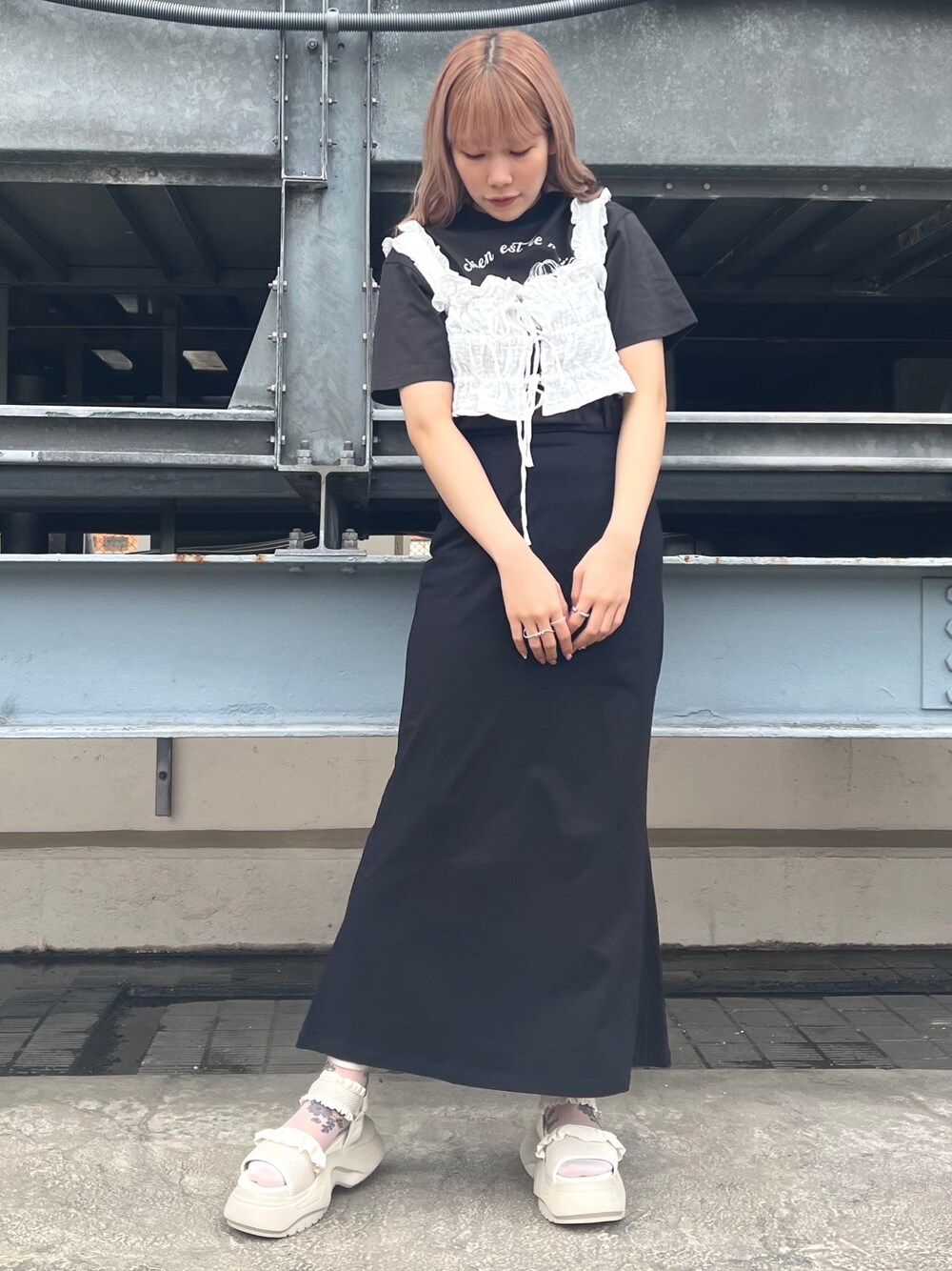 ホワイト系のベスト、グレー系のTシャツ/カットソー、ブラック系のスカートを着用したレディースの春コーディネートの1枚目の写真