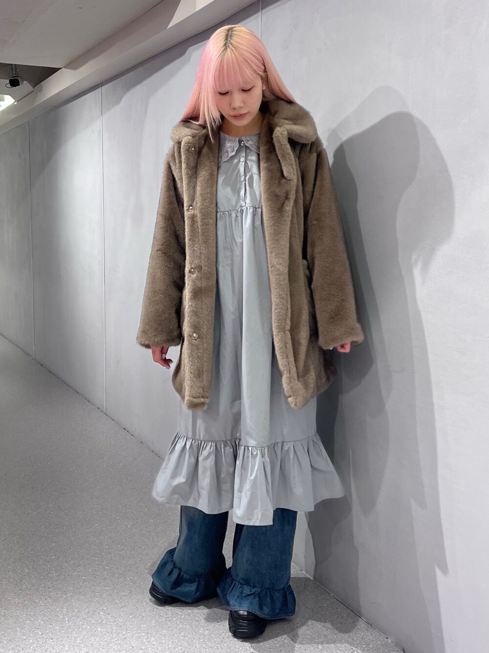 ブラウン系のノーカラーコート、グレー系のワンピース、ブルー系のデニムパンツを着用したレディースの冬コーディネートの1枚目の写真