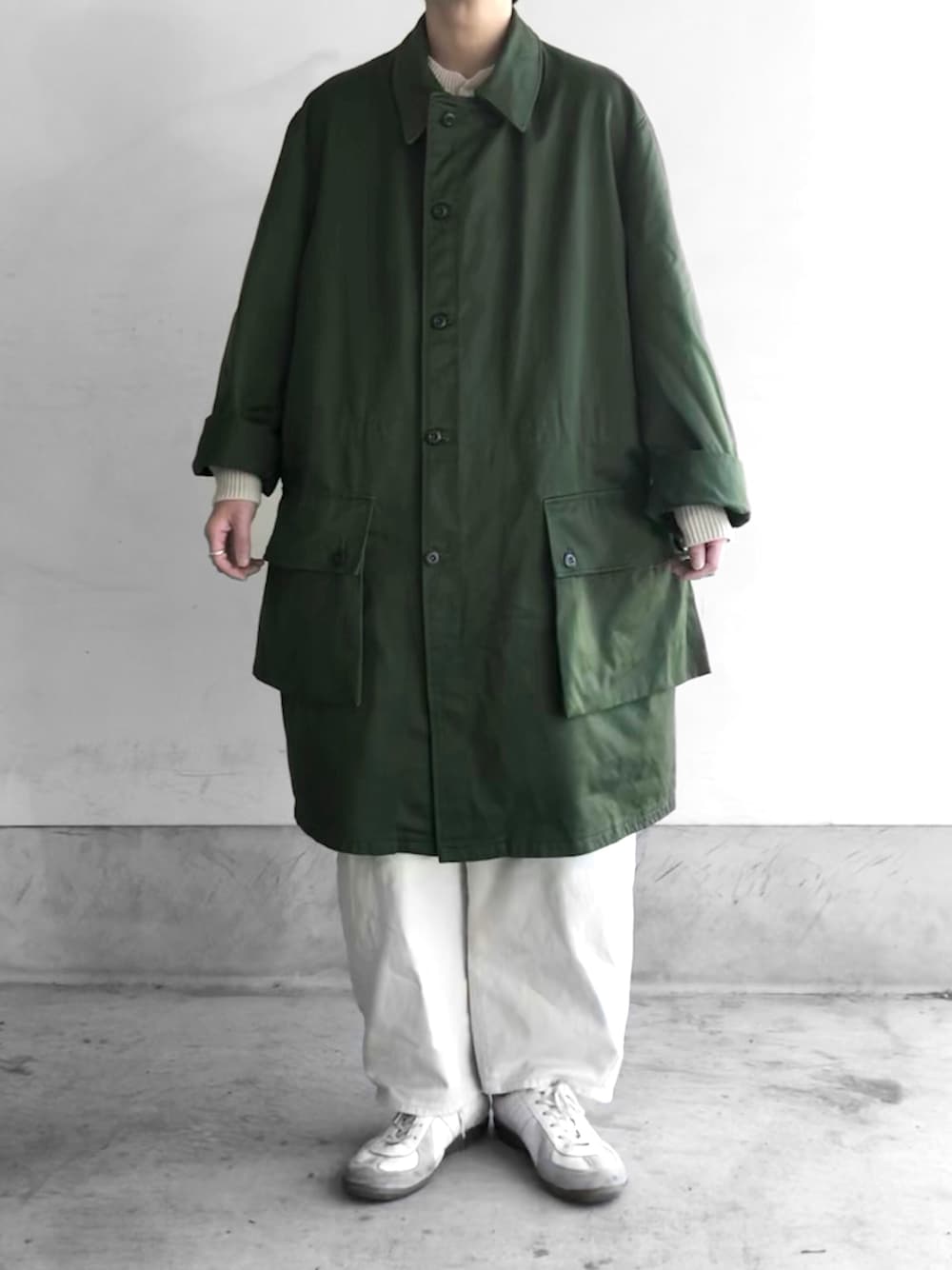 グリーン系のミリタリージャケット、グレー系のニット/セーター、ホワイト系のその他パンツを着用したメンズの冬コーディネートの1枚目の写真