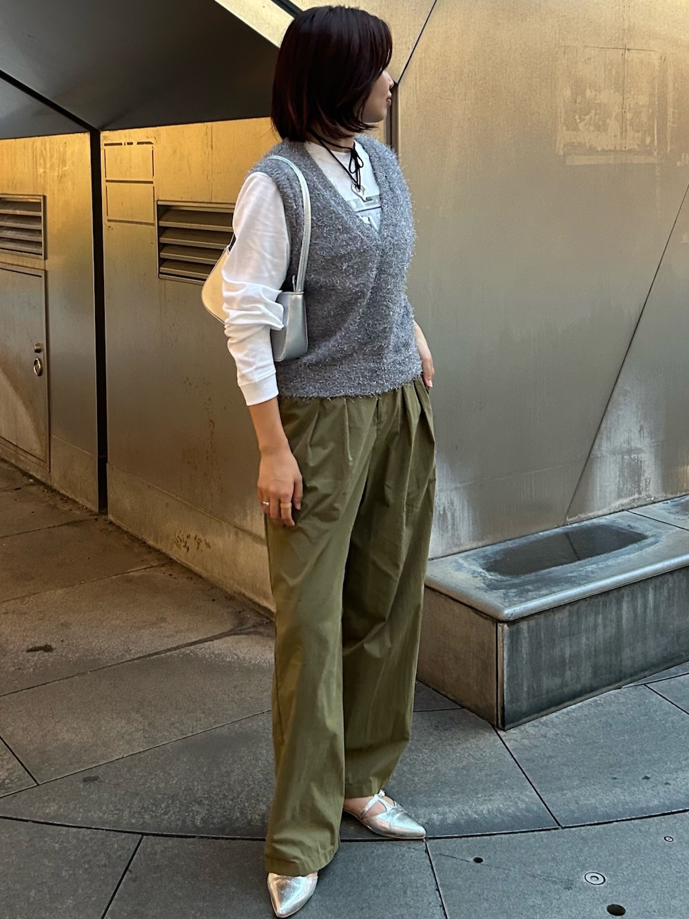 グリーン系のその他パンツ、グレー系のベスト、シルバー系のハンドバッグを着用したレディースの秋コーディネートの1枚目の写真