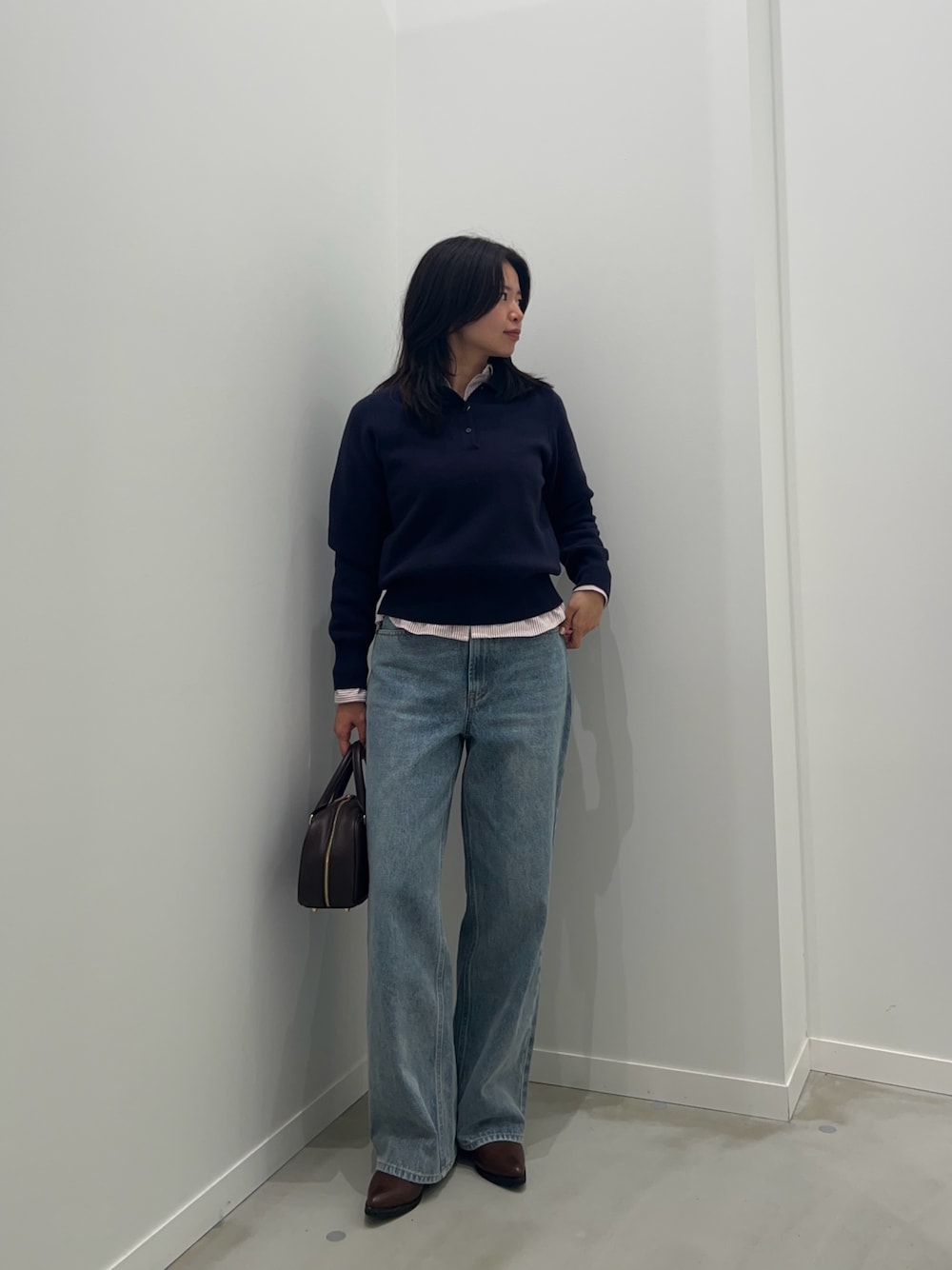 レッド系のシャツ/ブラウス、ブルー系のデニムパンツ、ブラウン系のボストンバッグを着用したレディースの秋コーディネートの1枚目の写真