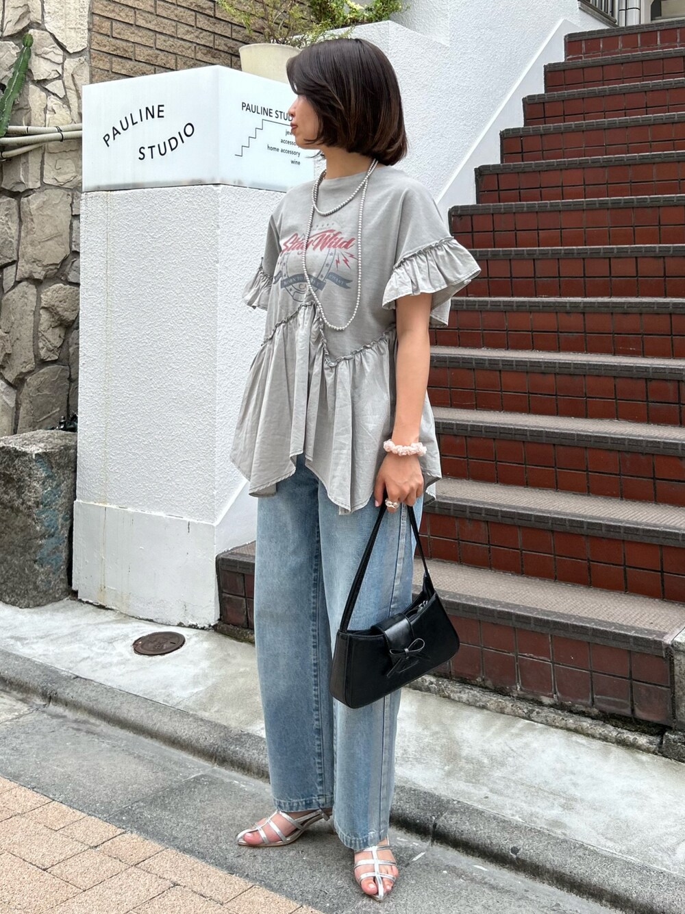 グレー系のTシャツ/カットソー、ブラック系のハンドバッグ、シルバー系のサンダルを着用したレディースの夏コーディネートの1枚目の写真