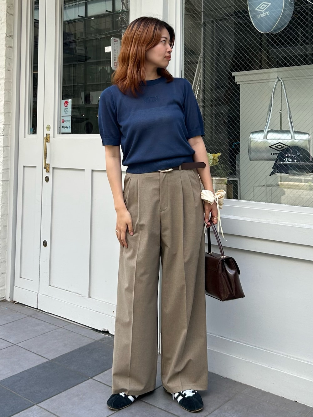 ブルー系のニット/セーター、イエロー系のスラックス、ブラウン系のショルダーバッグを着用したレディースの夏コーディネートの1枚目の写真