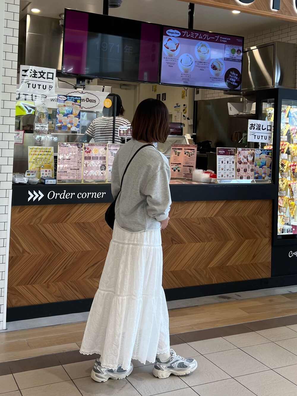 グレー系のスウェット、ホワイト系のスカート、ブルー系のバンダナ/スカーフを着用したレディースの春コーディネートの1枚目の写真