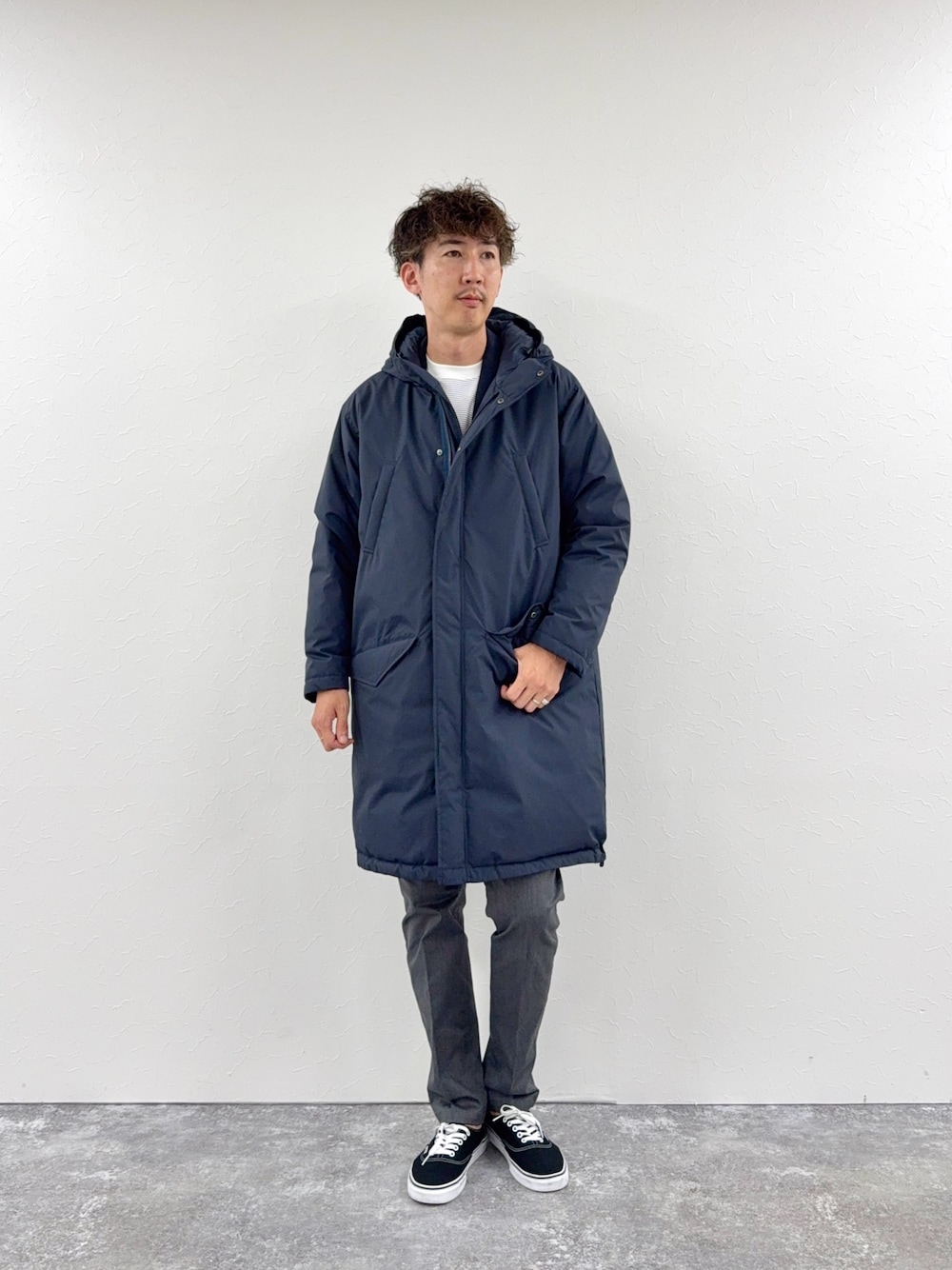 グレー系のチノパンツ、ホワイト系のTシャツ/カットソー、ブルー系のダウンジャケット/コートを着用したメンズの秋コーディネートの1枚目の写真