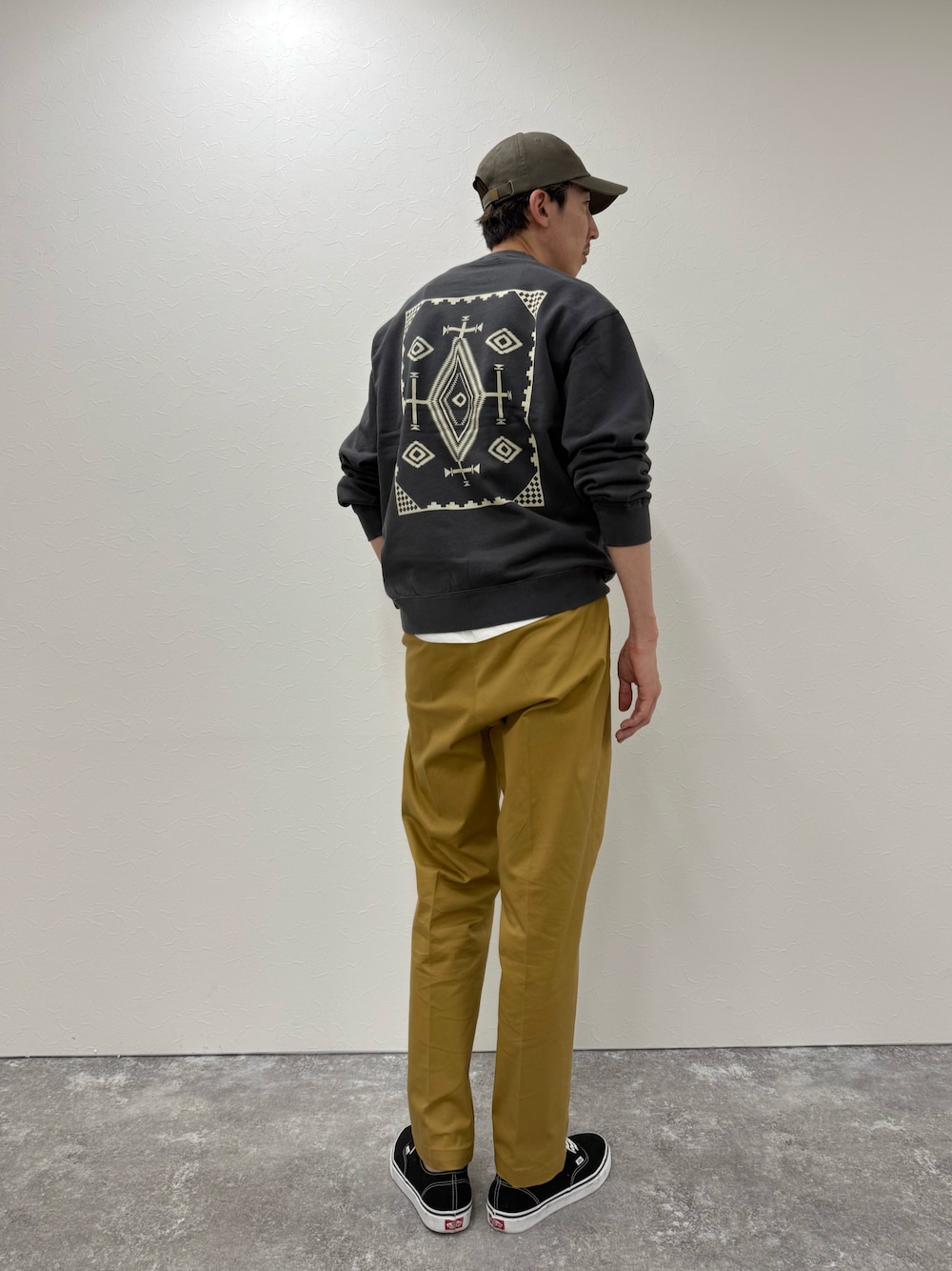 グレー系のスウェット、ベージュ系のチノパンツ、ブルー系のキャップを着用したメンズの秋コーディネートの1枚目の写真