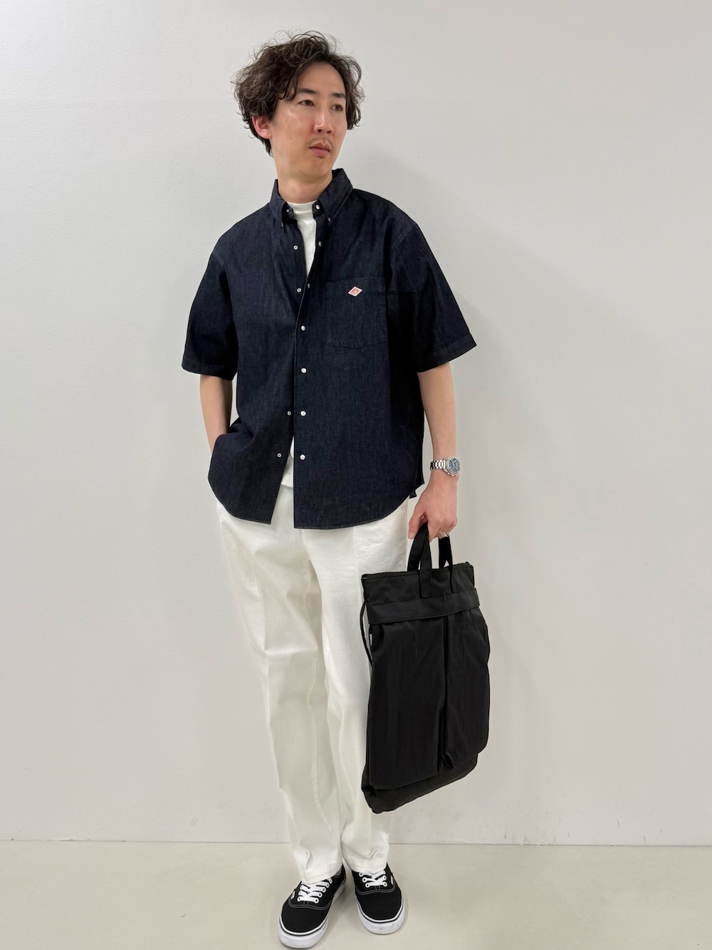 ブルー系のシャツ/ブラウス、ブラック系のトートバッグ、ホワイト系のデニムパンツを着用したメンズの春コーディネートの1枚目の写真