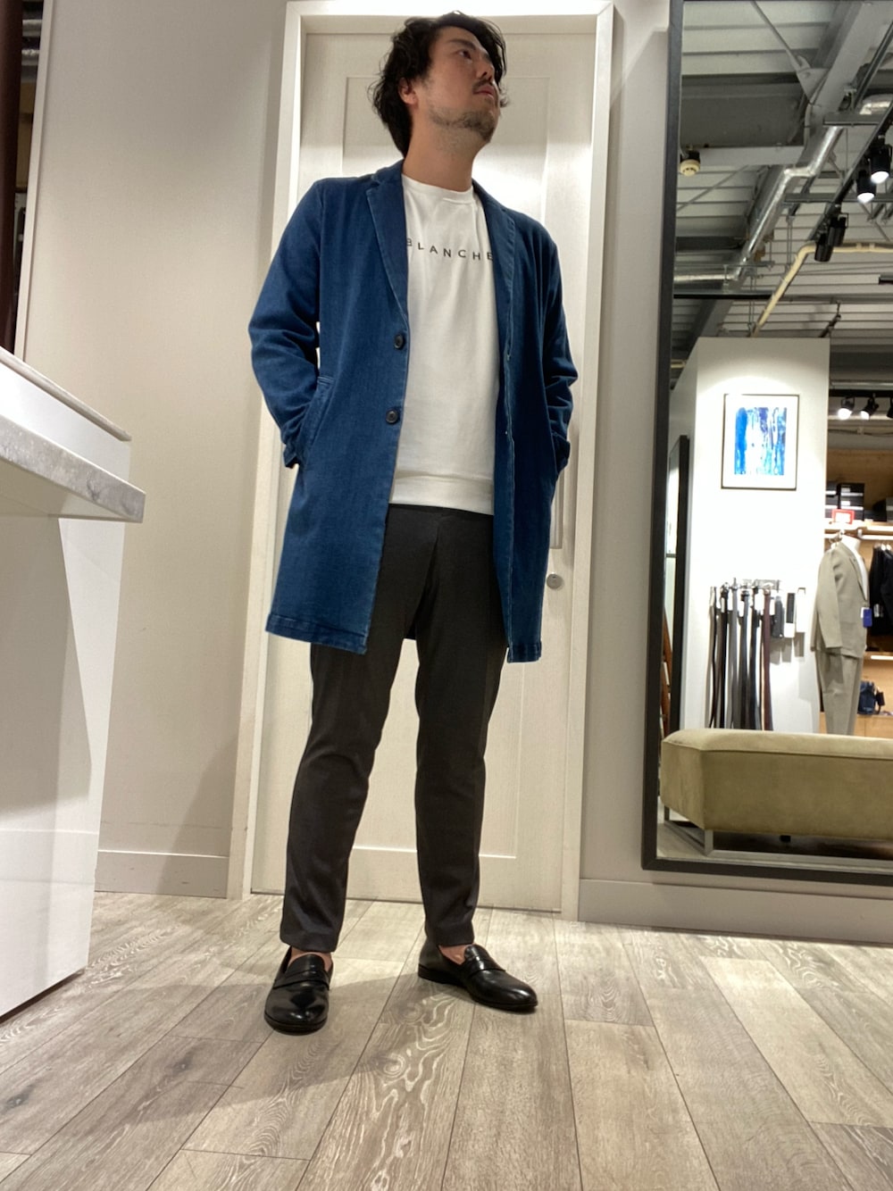 ブルー系のトレンチコート、ホワイト系のTシャツ/カットソー、グレー系のスラックスを着用したメンズの秋コーディネートの1枚目の写真