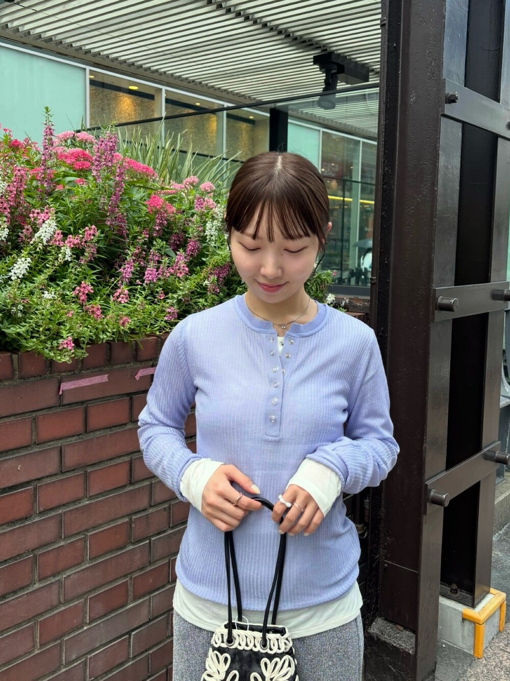 パープル系のニット/セーター、ホワイト系のTシャツ/カットソー、グレー系のスカートを着用したレディースの夏コーディネートの1枚目の写真