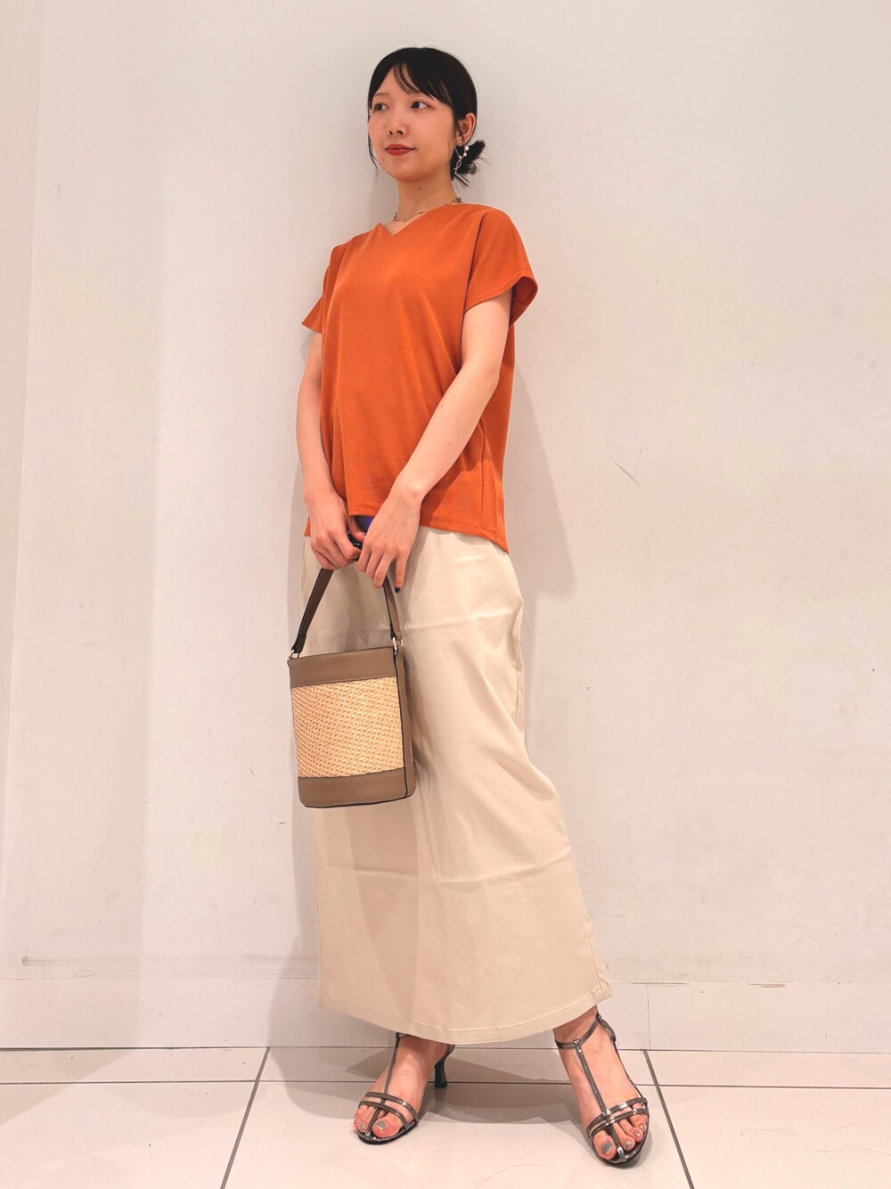オレンジ系のTシャツ/カットソー、グレー系のショルダーバッグ、ベージュ系のスカートを着用したレディースの夏コーディネートの1枚目の写真