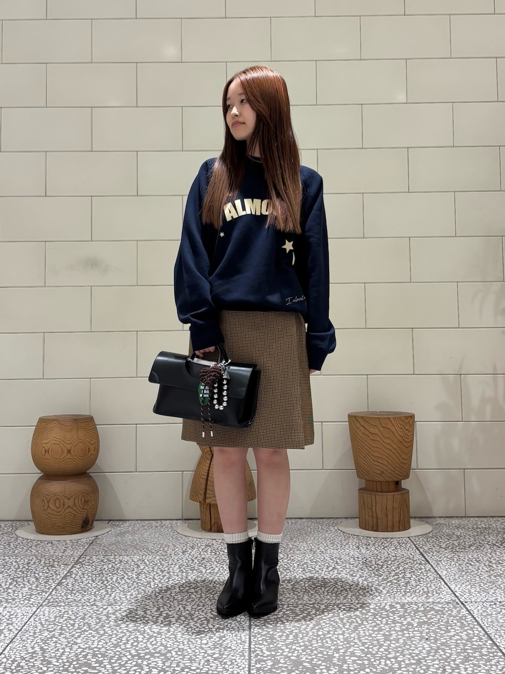 ブルー系のスウェット、イエロー系のスカート、ブラック系のハンドバッグを着用したレディースの秋コーディネートの1枚目の写真