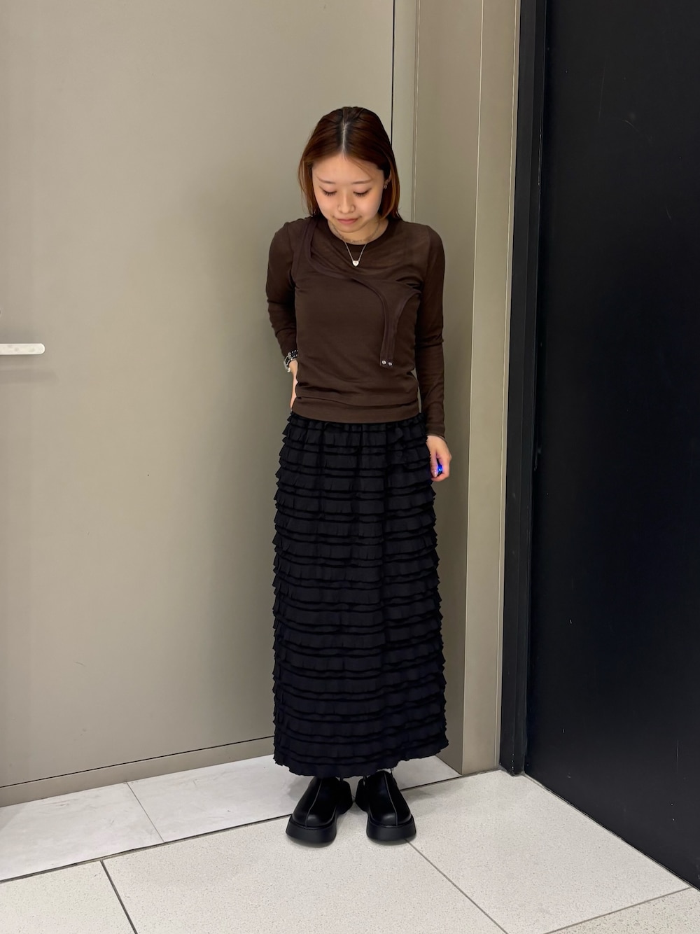 ブラック系のスカート、ブラウン系のTシャツ/カットソー、ブラック系のサンダルを着用したレディースの秋コーディネートの1枚目の写真