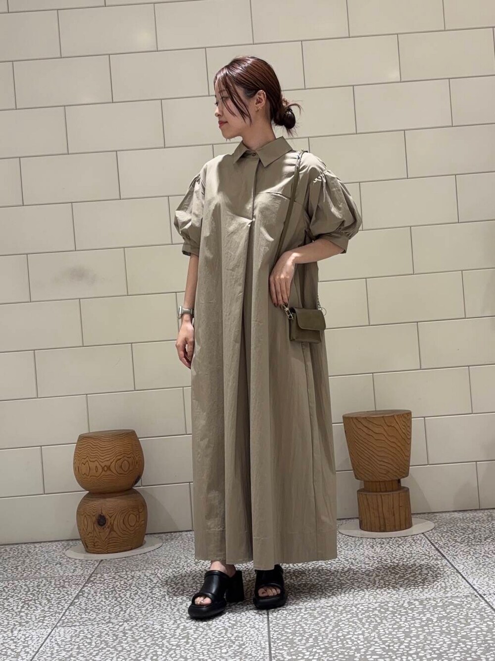 グリーン系のショルダーバッグ、ベージュ系のワンピースを着用したレディースの夏コーディネートの1枚目の写真