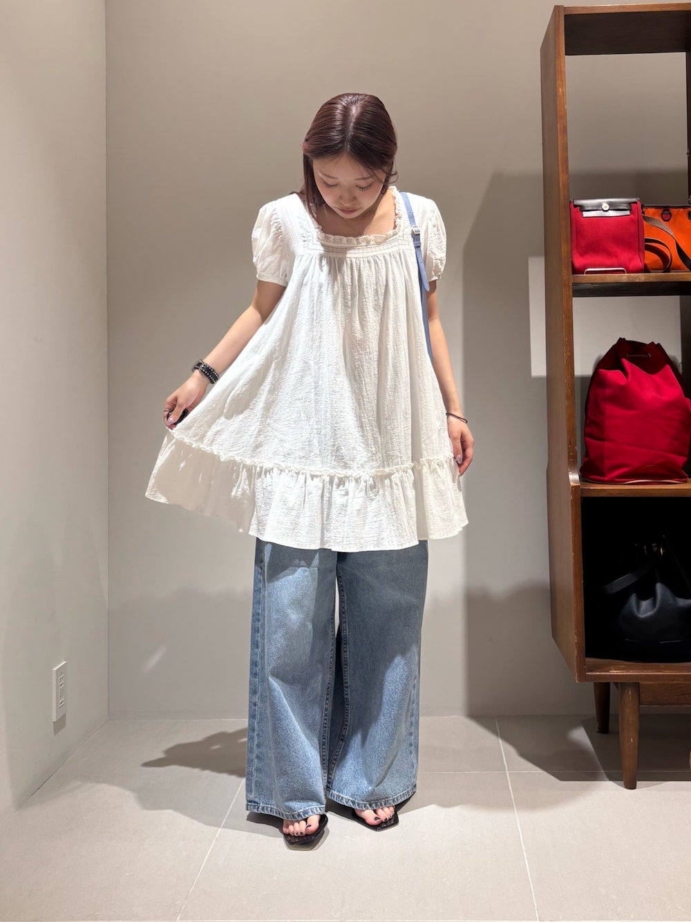 ホワイト系のシャツ/ブラウス、ブルー系のデニムパンツ、ブラック系のサンダルを着用したレディースの夏コーディネートの1枚目の写真