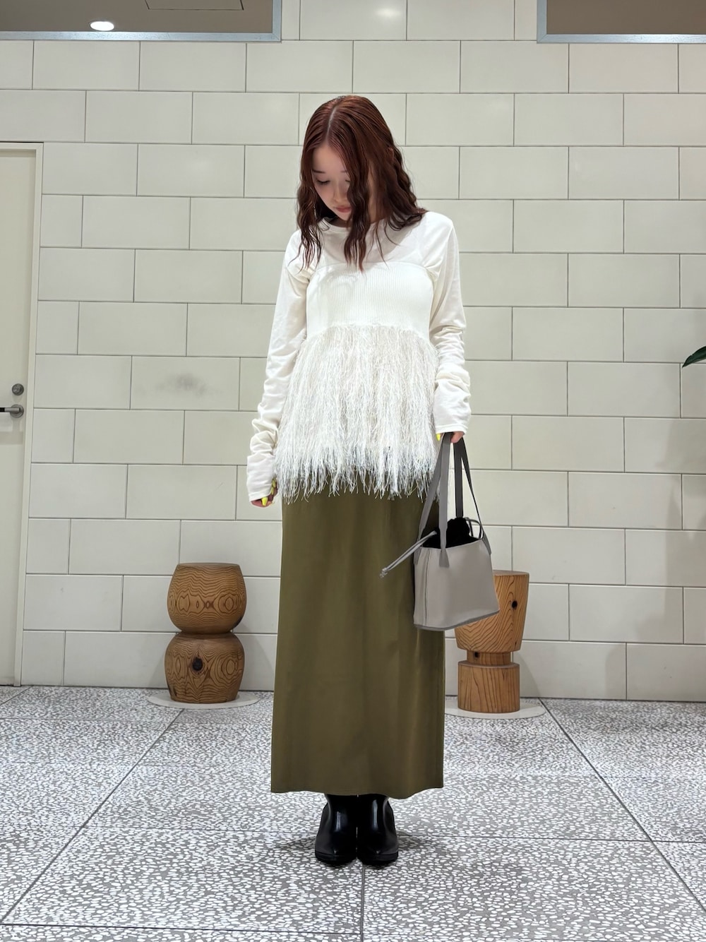 ホワイト系のTシャツ/カットソー、ホワイト系のニット/セーター、グリーン系のスカートを着用したレディースの秋コーディネートの1枚目の写真